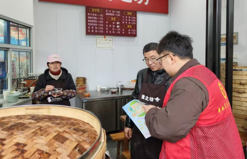 志愿者向沿街商铺宣传垃圾分类。