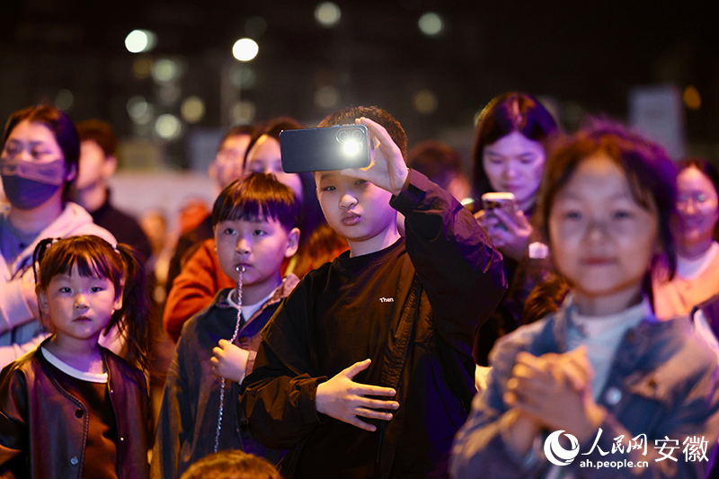 小朋友举起手机拍摄演出。人民网记者 陶涛摄