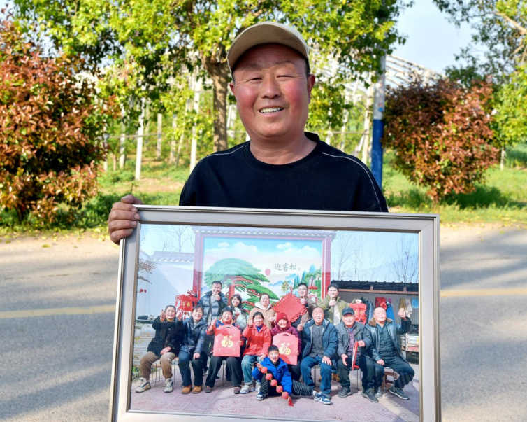 村民纪远华高兴地接过全家福照片。 李艳龙 摄