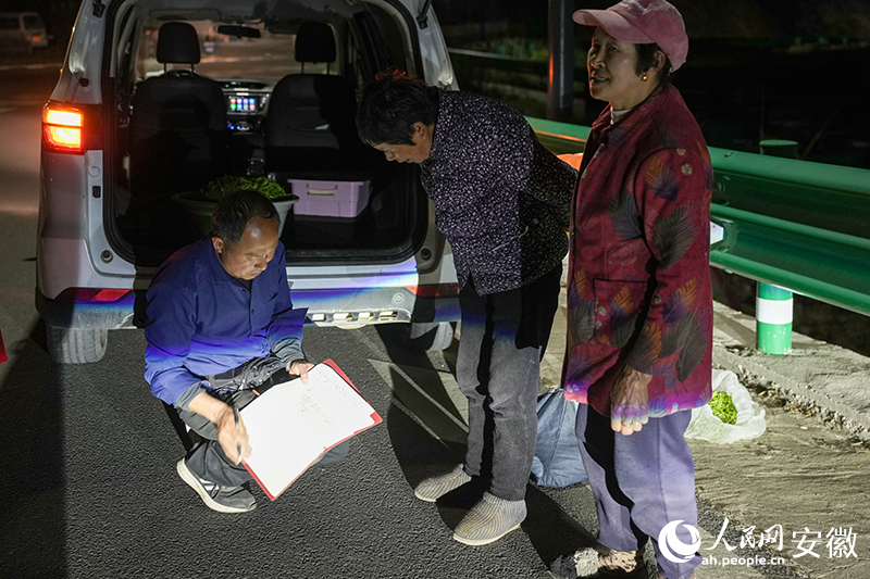 大湾村的山路边汪达海借着灯光在为茶农算收入。人民网记者 王锐摄