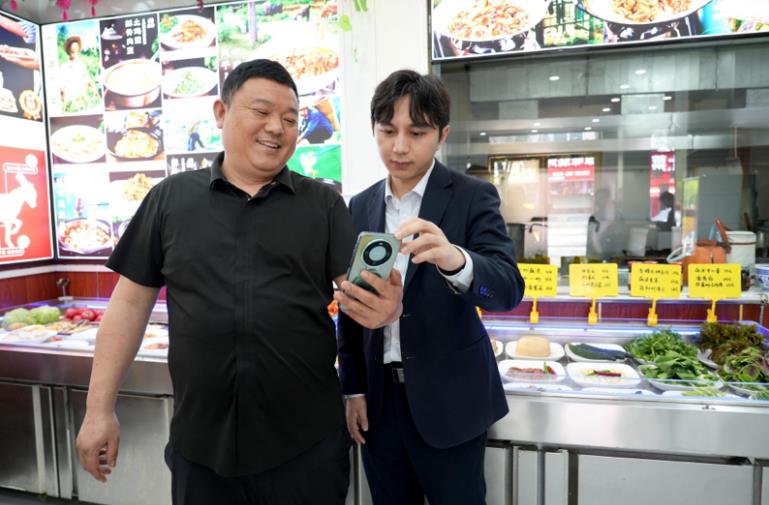 工行工作人员为餐饮店主介绍“烟火贷”产品。