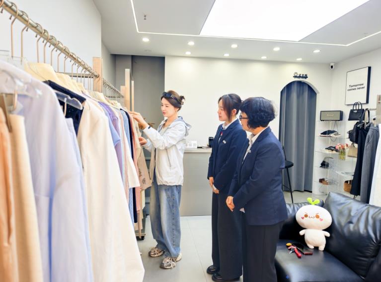 服装店负责人向工行工作人员介绍上新女装。