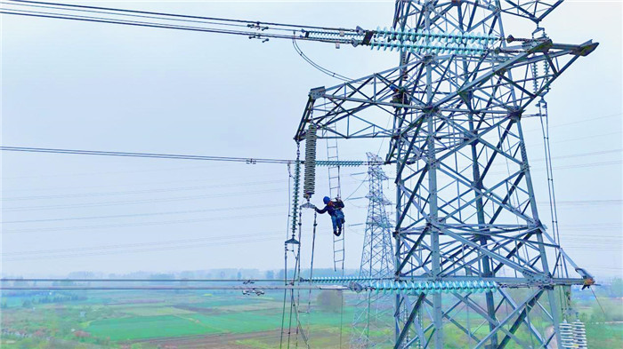 作業人員正在高空開展輸電線路絕緣子串安裝。
