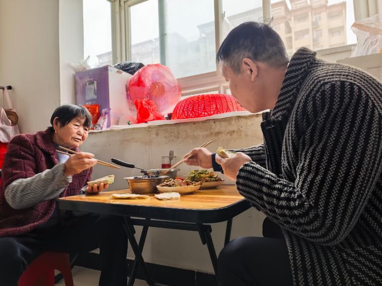 王计新（右）和家人在暖新公寓里吃饭。