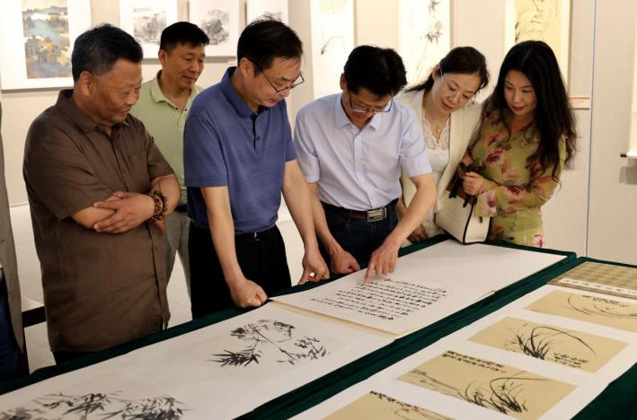 書畫愛好者在欣賞書畫作品。