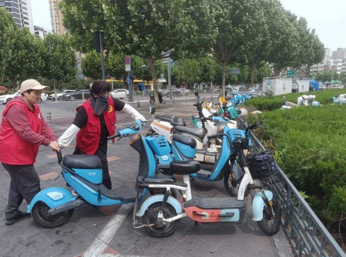 在五里墩街道，志愿者在摆放共享单车。