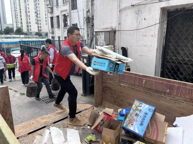 在三里庵街道大富新村小区，党员干部正在清理垃圾。