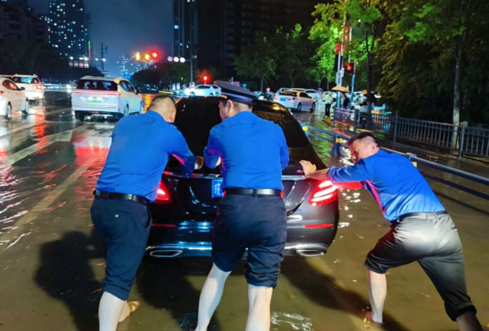 城管隊員幫助涉水熄火車主推車，暢通道路。