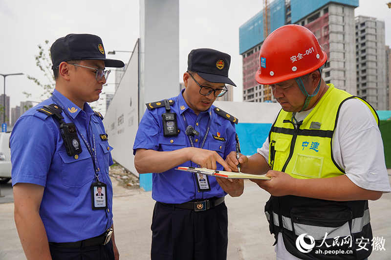 城管隊員對在建工地提示中高考期間施工要求。人民網記者 陳若天攝
