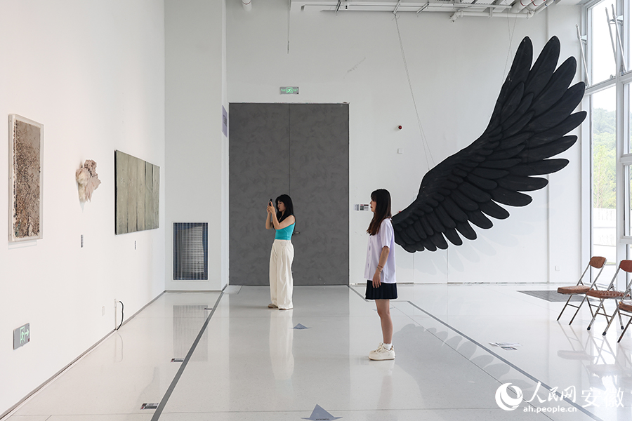 游客与作品《在场之缺》的翅膀浑然一体。人民网记者 张俊摄