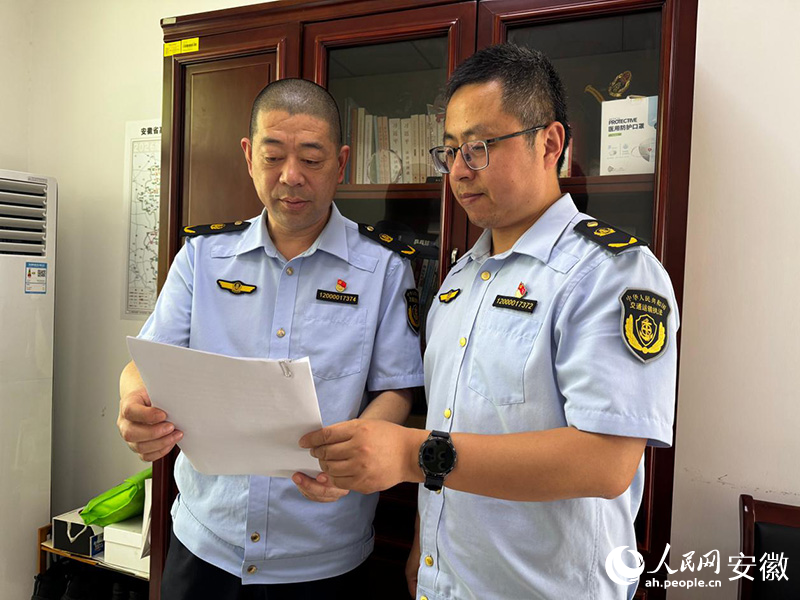 韩文胜（左）与同事沟通近期执法注意事项。人民网记者 胡雨松摄