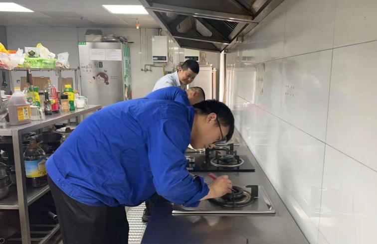 “吴雄飞爱心班”成员正在对故障灶具进行维修。