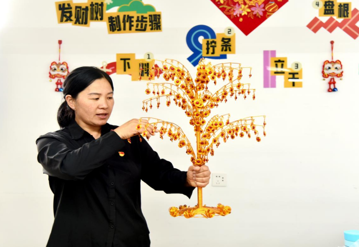 杨秋菊为员工讲解发财树的编织方法。 李艳龙 摄