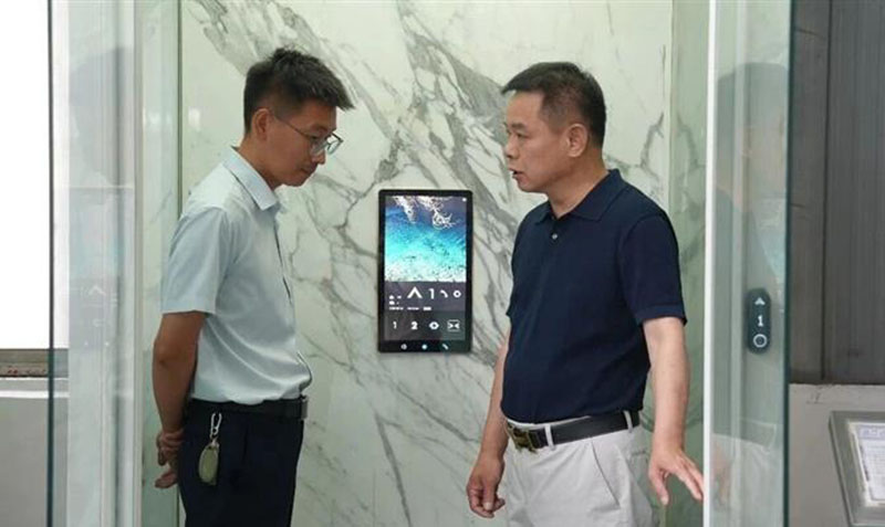 上海迅立达电梯公司董事长贺杰(右)查看加装电梯。