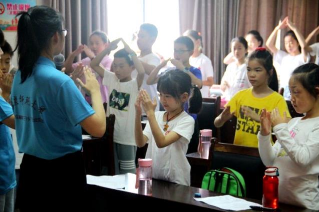 2019年，范俊楠（蓝色上衣）作为安庆师范大学暑期三下乡队长，在芭茅巷社区为孩子们教授手语。范俊楠供图