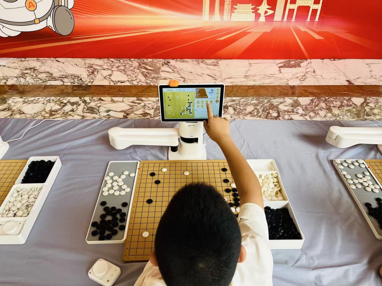 全国定段赛首日比赛前，一名小选手与围棋机器人对弈。淘云科技供图