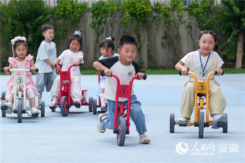 幼儿园里，孩子们在操场上骑车追逐。人民网记者 苗子健摄