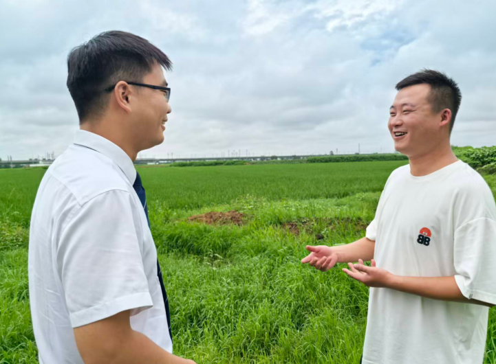 颍淮農商行霍邱支行客戶經理在田地裡為陳鵬介紹“擁軍貸”