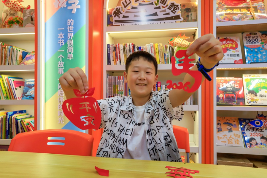 男孩展示刚刚制作出的剪纸作品。潘祯祥摄