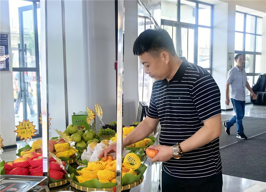 在太白岛服务区应季鲜果展销专区，旅客正在挑选购买水果。