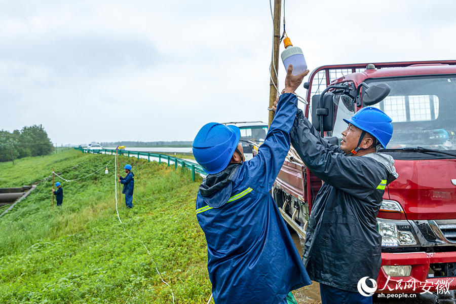 国网和县供电公司抢险队员正在冒雨架设防汛灯具。人民网记者 李希蒙摄