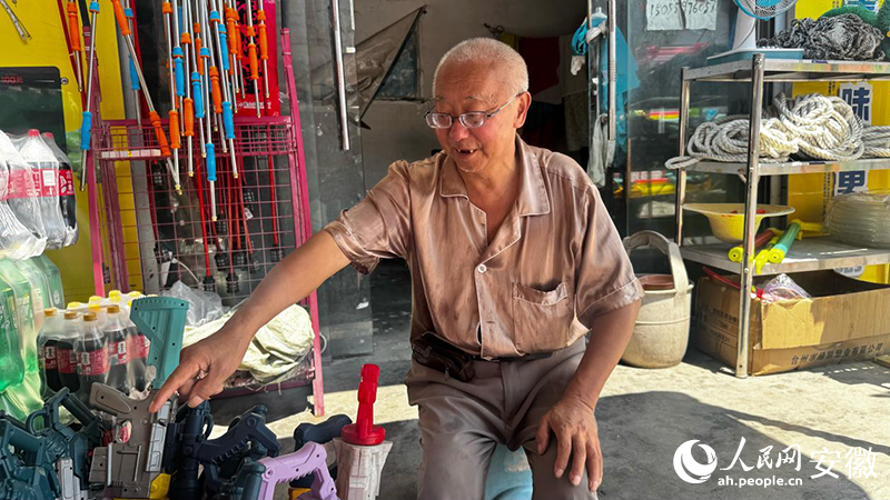 坐在理发店门口卖漂流用品的林维安。人民网 郭昊摄