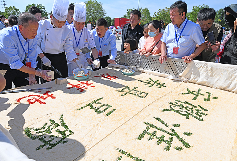 10月5日，游客在安徽省淮南市壽縣古城千人豆腐宴現場品嘗一塊3000斤重的大豆腐。陳彬攝