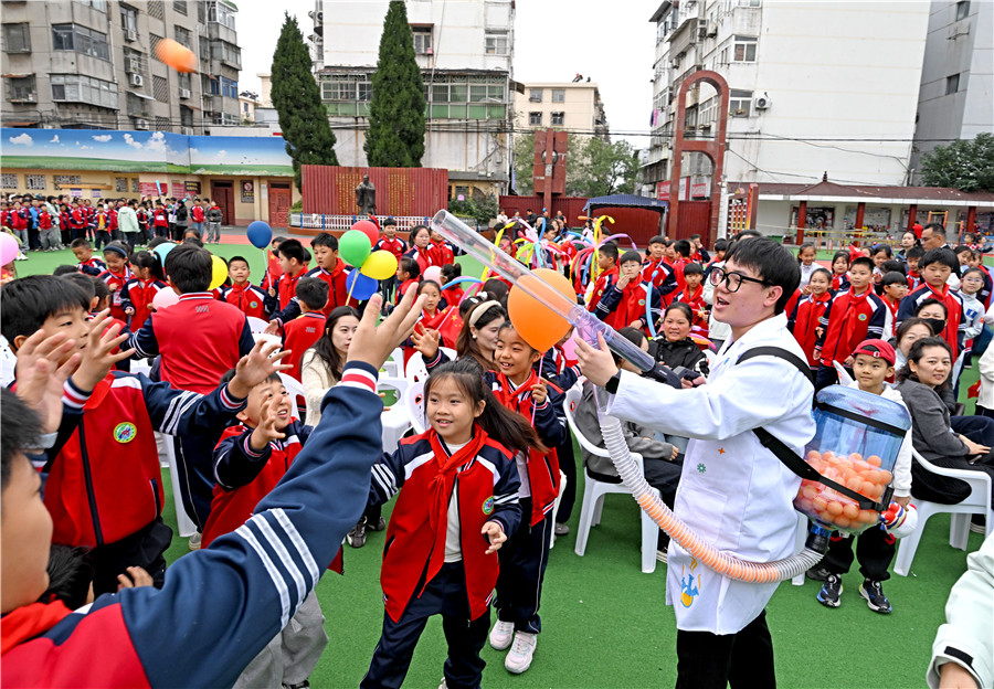 小学生在“乒乓球机关枪”科学游戏中玩乐。