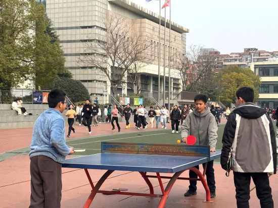 在合肥市五十中天鹅湖教育集团天鹅湖校区的操场上，同学们正在打乒乓球。