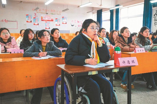 3月13日,在安徽师范大学田家炳教学楼101教室,许詹琪正在认真听课,占群燕坐在她的身后,专心给她做笔记。目前,“妈妈笔记”已累积了30余本。