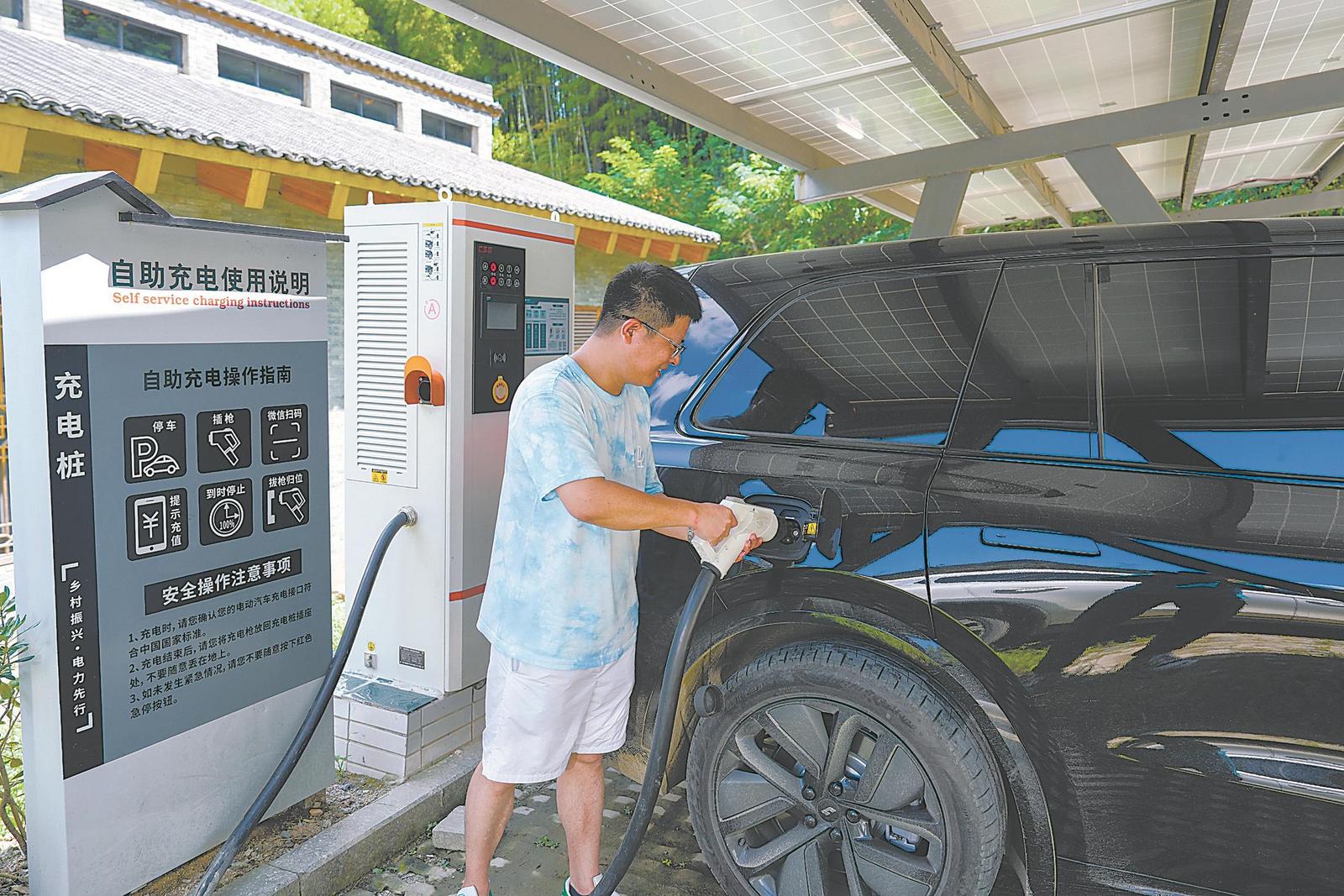 在金寨縣花石鄉大灣村，來自武漢的游客楊先生在光伏、充電一體化5G智能充電站為車輛充電。