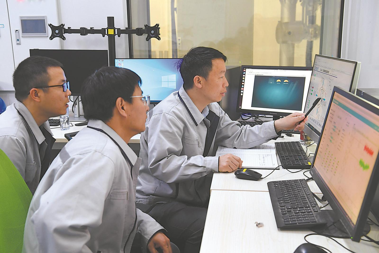 4月21日，在中科離子醫學技術裝備有限公司，丁開忠（右一）與同事觀察磁體組系統運行情況。